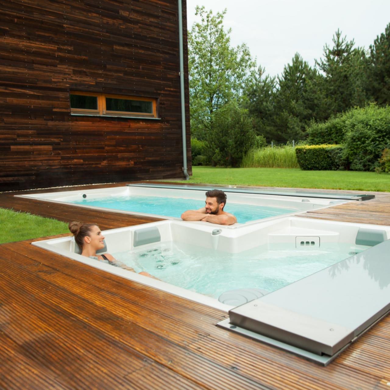 Par kopplar av i utomhus USSPA spa och simbassänger installerade på en träterrass